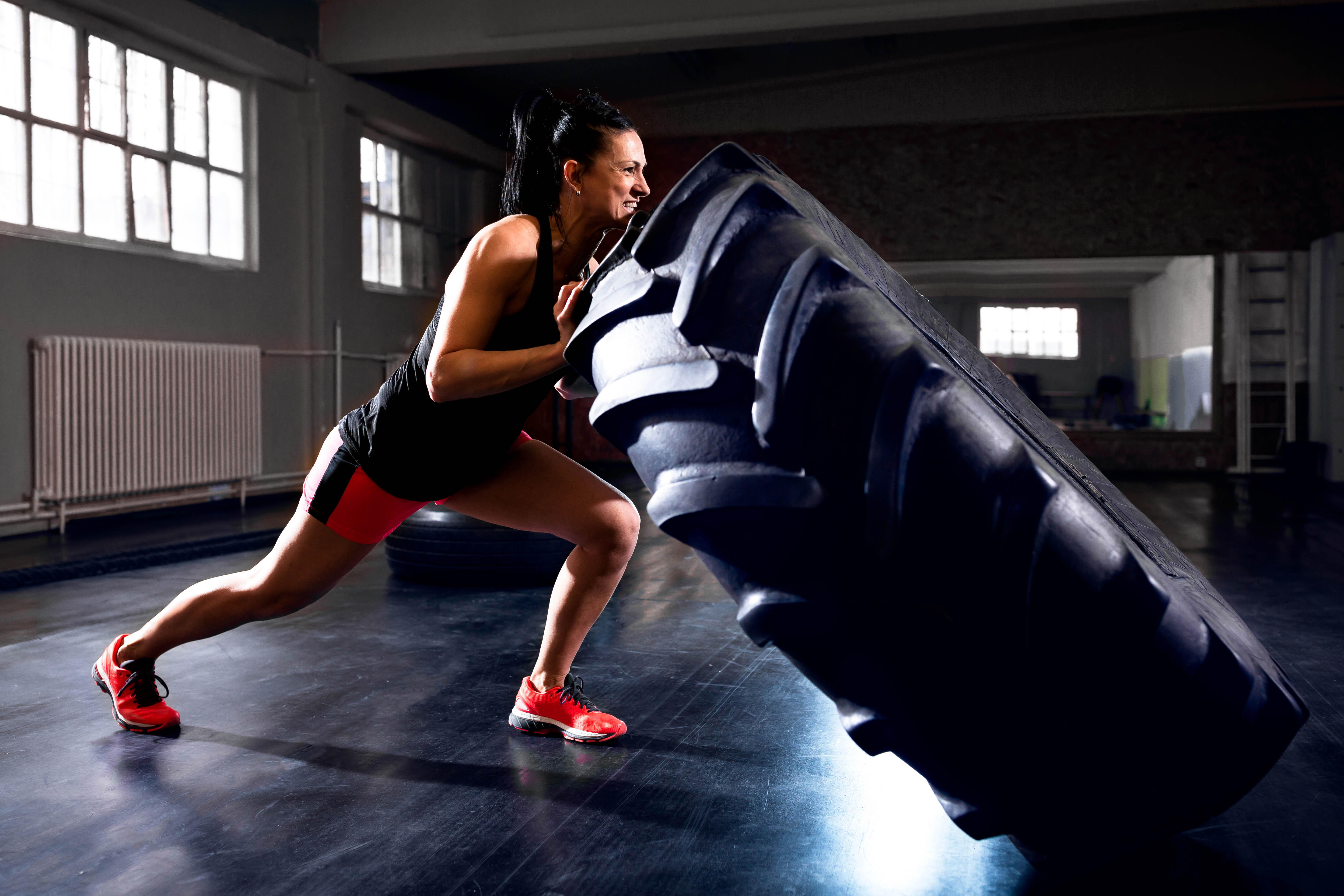 Younger woman flipping a tire in a gym setting